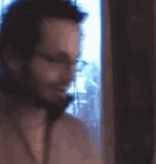 a blurry picture of a man with glasses looking out of a window