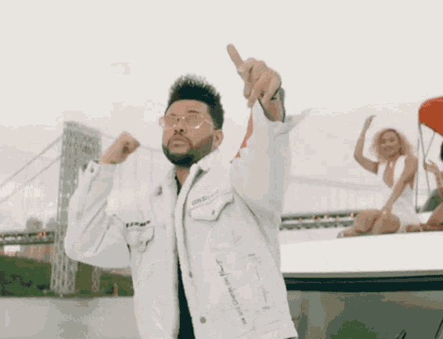 a man wearing sunglasses and a white jacket is standing in front of a group of women sitting on a boat .