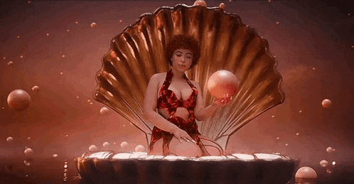 a woman in a red dress is sitting in a shell holding a ball .