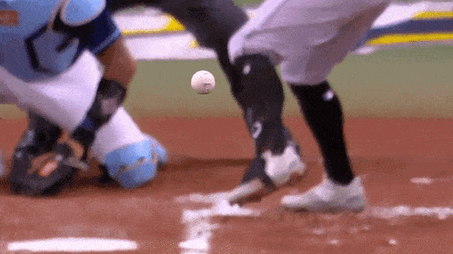 a baseball player is trying to catch a ball while a catcher looks on .