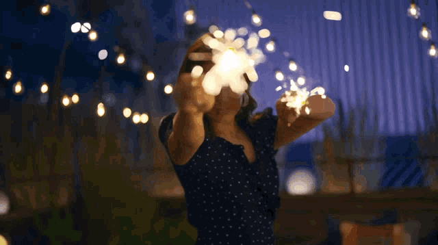 a woman in a polka dot dress is holding sparklers