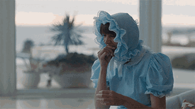 a woman wearing a blue dress and a blue baby hat