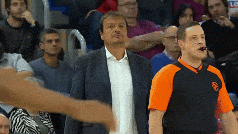 a man in a suit stands next to a man in an orange shirt with the letter a on it