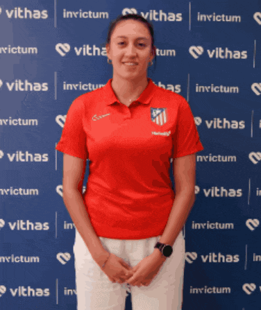 a woman in a red shirt stands in front of a blue wall that says invictum on it