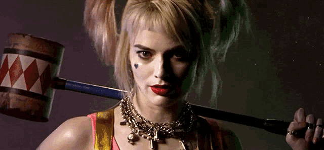 a woman in a harley quinn costume is holding a hammer .