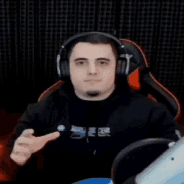 a man wearing headphones and a black shirt is sitting in a chair .