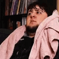 a man with a beard is sitting in a chair with a pink towel around his neck