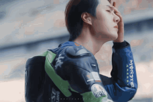 a man wearing a monster energy jacket holds his hand to his forehead