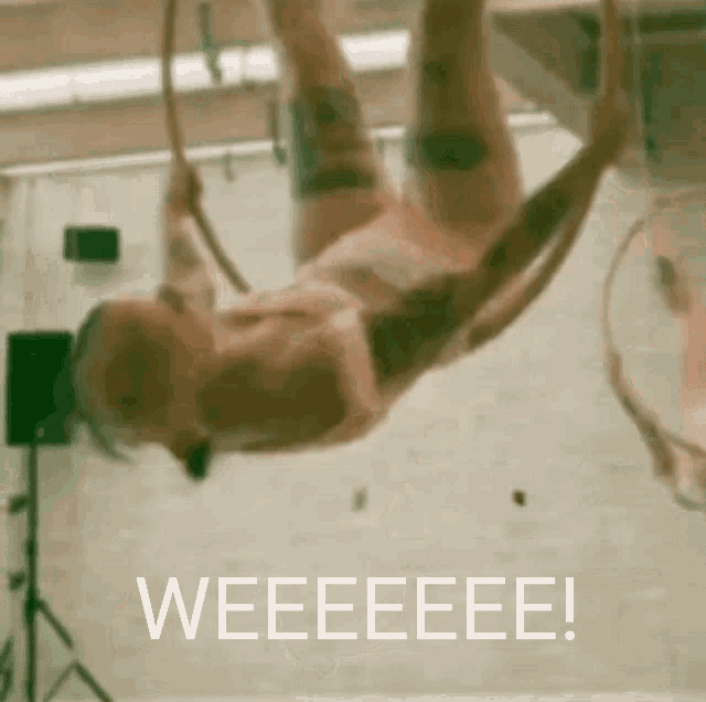 a woman is hanging upside down on an aerial hoop with the words weeeeeee behind her