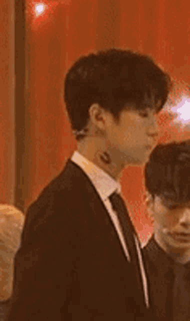 a man in a suit and tie with a tattoo on his neck .