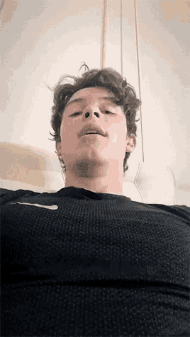a young man is laying on a bed with his mouth open and his chest exposed .