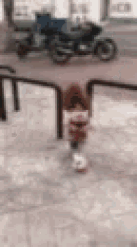 a blurry picture of a person walking down a sidewalk with a motorcycle parked in the background .