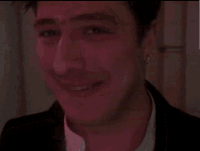 a man with a nose ring is smiling in a dark room