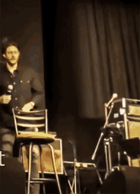 a man sits in a chair on a stage with a microphone