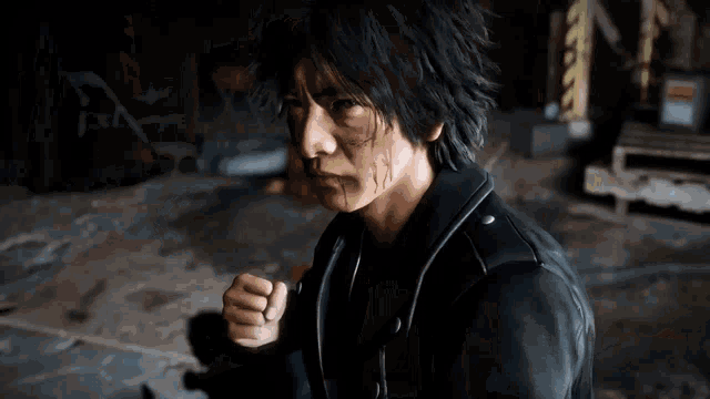 a man wearing a black leather jacket is standing in a dark room with his arms outstretched .