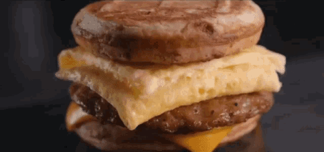a close up of a breakfast sandwich with eggs , cheese and sausage