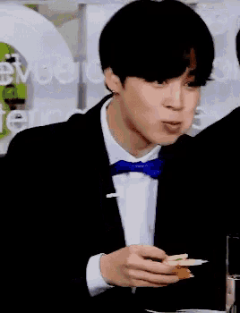 a man in a suit and tie is eating a piece of food .