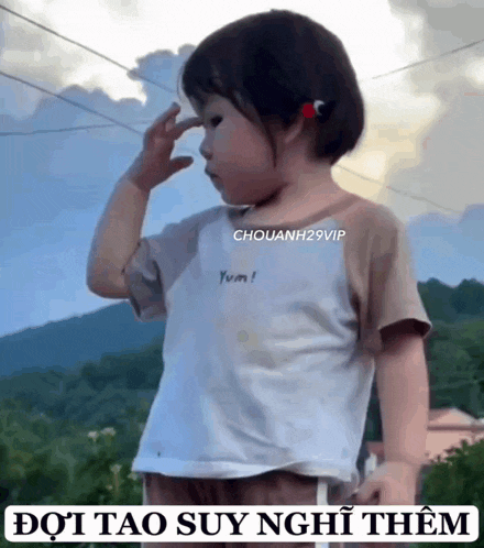 a little girl in a white shirt is saluting with her hand on her forehead .