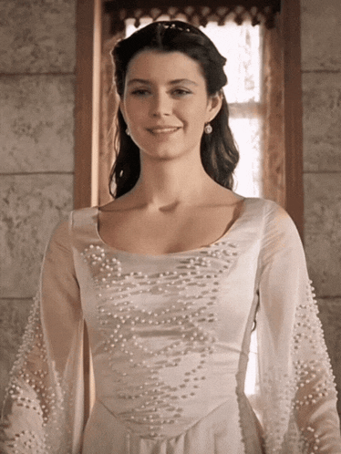 a woman is wearing a white dress with pearls on the sleeves