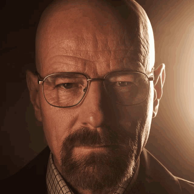 a bald man with glasses and a beard looks serious