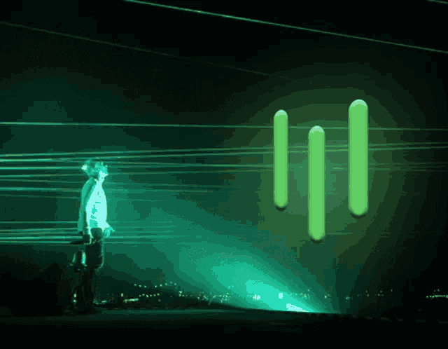 a man in a white shirt stands in front of a green glowing logo