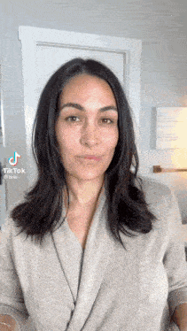 a woman without makeup is standing in front of a door in a room and looking at the camera .
