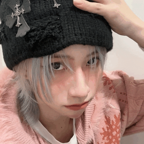 a girl wearing a black beanie with a cross on it