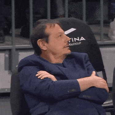 a man in a suit is sitting in a chair that says na group on it