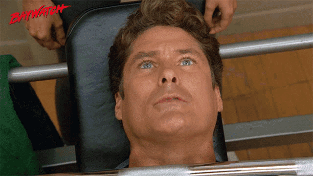 a man laying on a bench with the word baywatch on the top