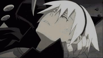 a person with white hair is laying on the ground with their eyes closed and a black jacket on .