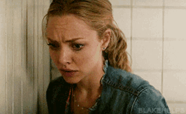 a woman in a denim jacket is standing next to a wall with blakerhelps written on it