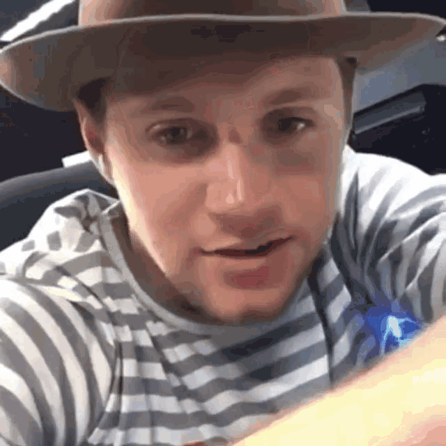 a close up of a man wearing a hat and a striped shirt