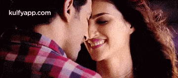 a man and a woman are kissing each other on the forehead .