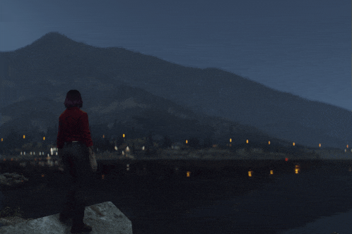 a woman in a red sweater stands on a rock overlooking a body of water with mountains in the background
