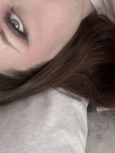 a close up of a woman 's face with a white pillow that says ' cherry ' on it