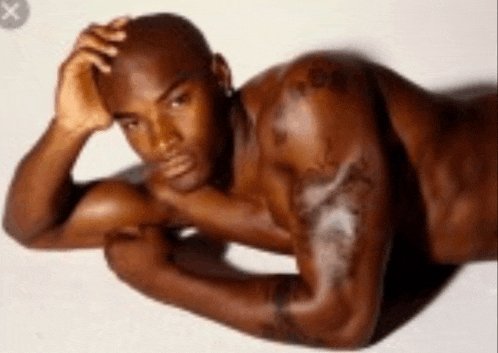 a naked man with a tattoo on his arm is laying down