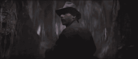 a man in a hat is looking up in a dark room