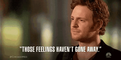 a man is standing in front of a sign that says `` those feelings haven 't gone away ''