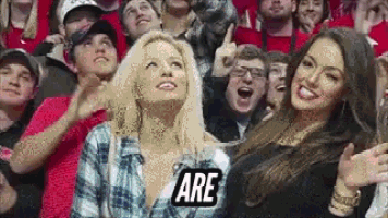 a group of people sitting in a stadium with a sign that says are on it