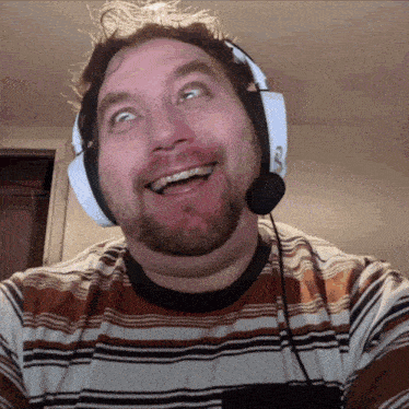a man wearing headphones and a microphone is smiling and making a funny face