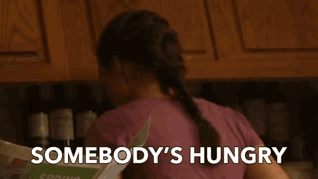 a woman is reading a newspaper and the words somebody 's hungry are on the screen