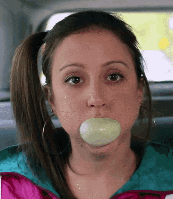 a woman is blowing a bubble with a piece of soap in her mouth