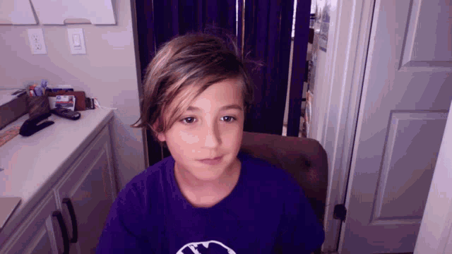 a young boy wearing a purple shirt with a circle on it