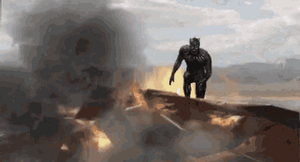 a man in a black suit is standing on top of a burning vehicle