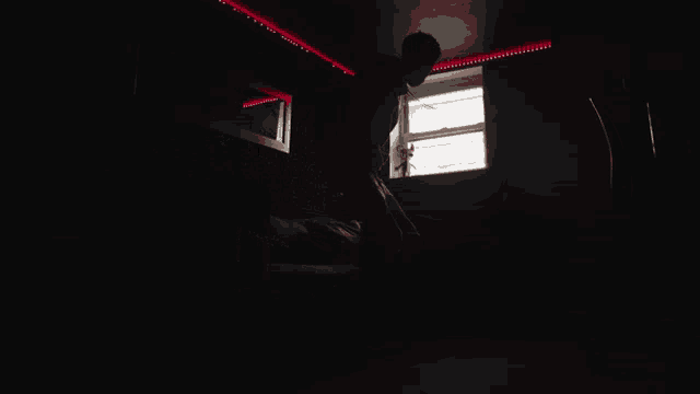 a man is standing in a dark room with a red light on the ceiling