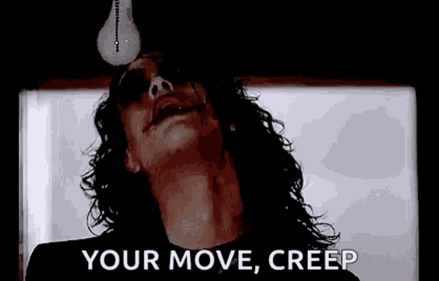 a man with long hair is holding a light bulb in his mouth and screaming .