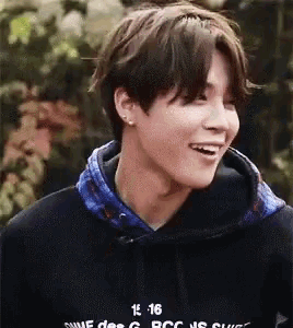 a close up of a young man wearing a black hoodie and smiling .