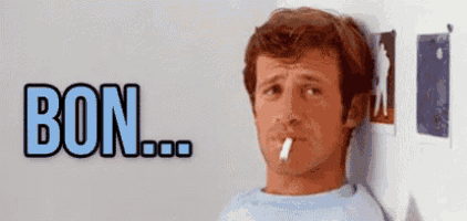 a man is leaning against a wall and smoking a cigarette .