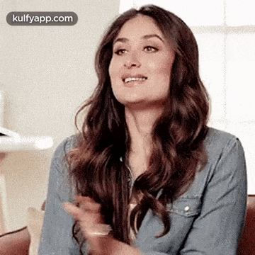 a woman in a denim jacket is clapping her hands while smiling .