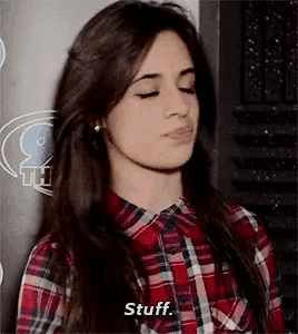 a woman in a plaid shirt is making a funny face and says stuff .